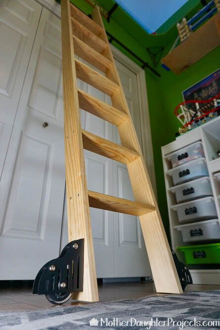 How to Build a Rolling Library Ladder - Mother Daughter Projects Diy Sliding Library Ladder, Library Ladder To Loft, Diy Sliding Ladder, Wood Ladder Diy, High Kitchen Cabinets, Diy Library Ladder, Library Ladders Rolling, Diy Wood Ladder, Diy Wooden Ladder