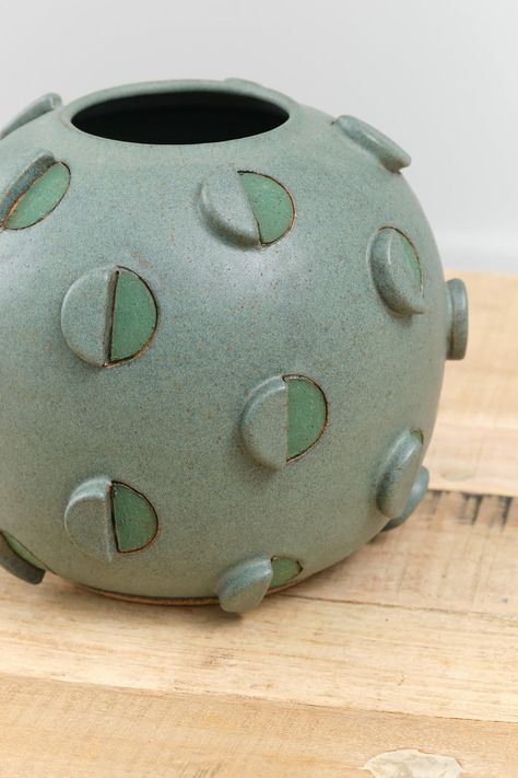 The Barrel Cactus Vase is a large decorative and functional bulbous vase with an abstract circle design throughout in a rich green glaze. Hand-carved and hand-painted geometric and three dimensional circle details adorn the exterior of the vase, finished with a Matthew Ward signature at the base. Ceramic Pouring Bowl, Contemporary Ceramic Vase, Abstract Designs Pattern, Ceramic Trends 2024, Hand Built Ceramic Vase, Ceramic Urns For Ashes, Pinch Pot Projects, Ceramic Carving Designs, Functional Pottery Ideas