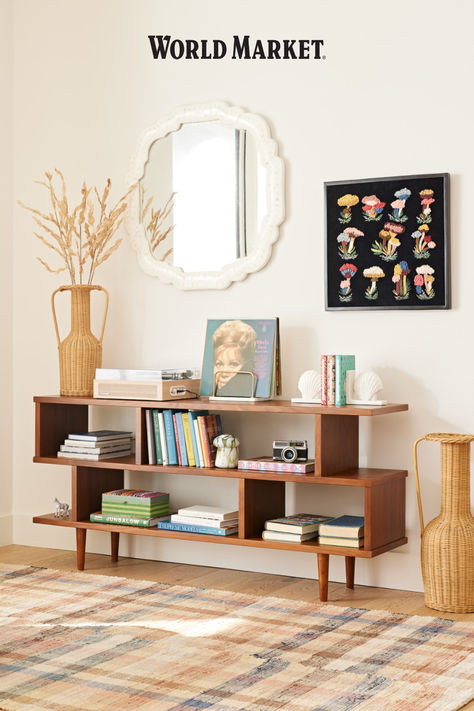 Featuring four roomy compartments, our bestselling mid-century-inspired Ashlyn bookcase offers ample storage space for books, framed photos and keepsakes. A rich medium-walnut stain highlights the wood construction of this asymmetrical shelf that doubles as a console table. #WorldMarket Bookshelf Console, Unique Living Room Furniture, Wood Bookshelf, Framed Photos, Wood Bookshelves, Modern Sofa Sectional, Cabinet Shelving, Wood Sideboard, Walnut Stain