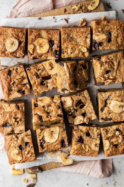 "These Banana Chocolate Chip Bars are a simple and delicious recipe using ripe bananas and store cupboard ingredients. Baked in 30 minutes, they make the perfect afternoon, easy snack to feed a crowd.  Sliced squares on banana chocolate chip bars on a wooden chopping board. We've all had ripe bananas sitting on our countertop, gradually getting more spotty as the days pass. This Banana Chocolate Chip Bars recipe is the perfect go-to, easy-to-make recipe for those bananas.  It's fast become one Banana Chocolate Chip Bars, Holiday Recipes Christmas Desserts, Halloween Food Desserts, Almond Pound Cakes, Homemade Doughnuts, Chocolate Chip Bars, Holiday Dessert Recipes, Easter Desserts Recipes, Thanksgiving Food Desserts