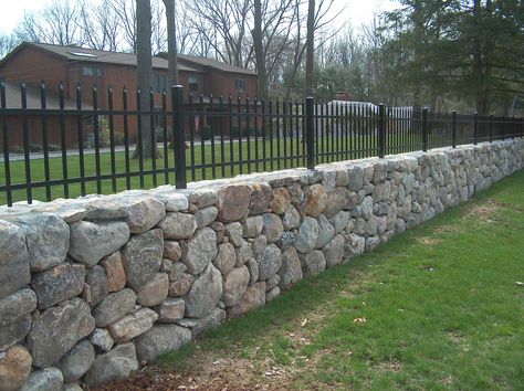 Rock Wall With Fence On Top, Wrought Iron Fence On Stone Wall, Stone Boundary Wall Design, Stone Perimeter Wall, Stone Wall Fence Ideas, Diy Stone Fence, Rock Fence Ideas, Stone Wall Outdoor Fence, Fence On Stone Wall