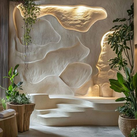 Transform interiors with sculptural plaster walls inspired by nature. This wave-like plaster design, enhanced with built-in planters and soft lighting, creates a serene and organic aesthetic, perfect for modern spaces. Ideal for biophilic design lovers, plaster’s versatility as a building material allows for creating immersive and calming environments that connect with nature. Wall Plastering Design, Organic Wall Art, Building Materials Architecture, House Jungle, Plaster Design, Content House, Plastered Walls, Fake Rock, Meditation Studio