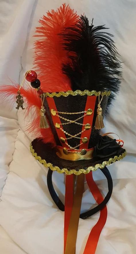 Circus Ringmaster mini black glitter top hat with satin headband. 1 x hatpin adorning pearls beads & a brass jester charm sits on side. Red & black ostrich feathers sit at back & a red chick feather & gold rooster feather sit on side. A black rose sits on other side & golden buttons are down front Circus Top Hat, Black Glitter Top, Circus Ringmaster, Ringmaster Costume, Jester Clown, Circus Dress, Ring Master, Circus Outfits, Lion Tamer