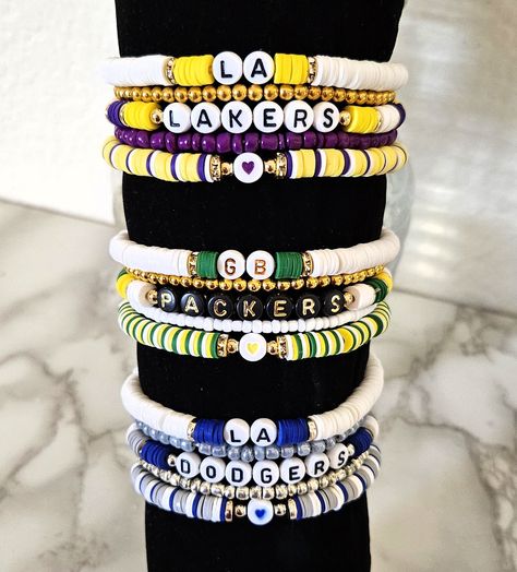 Represent your favorite team with this 5-piece bracelet stack. other teams available upon request. some stacks will vary on bead type based on colors. For Other sport option add personalization and specify team. Team Friendship Bracelets, Game Day Bracelet Stacks, Sports Teams Clay Bead Bracelets, College Beaded Bracelets, Baseball Heishi Bracelet, Team Beaded Bracelets, School Spirit Bracelets, Clay Bead Bracelet Ideas For Boys, Baddie Bracelets