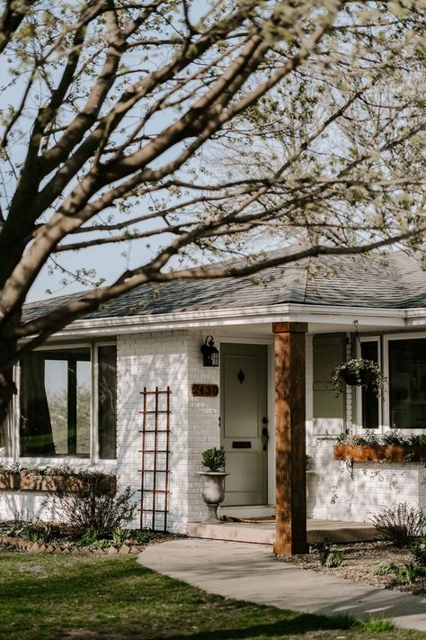 Here's our brick ranch exterior makeover and how we turned into a cottage! It's inspired by a French Country Cottage and there are lots of details to love such as board and batten shutters, DIY flowerboxes, a sage green front door, boxwood planters by the front door, and a painted white brick house! But actually, it's a limewashed brick home! Check out the post for all the details! Country Cottage Exterior, French Country Cottage Exterior, Brick Ranch Exterior, Limewashed Brick, Boxwood Planters, Shutters Diy, Brick Ranch Houses, Siding Ideas, Ranch House Exterior