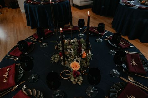 sweetheart table - dark wedding table decorations - Navy tablecloth with burgundy napkins and gold laser cut name place cards, gold silverwear and black plates and black wine glasses by ce rental - dark flowers centerpiece - gold table number - gold candle stick holder with black candles - Matt Smarsh and Johanna Dye - Raleigh North Carolina Urban Downtown Wedding at the Glass Box at 230 Round Table Centerpieces Wedding, Burgundy Napkins, Round Table Centerpieces, Black Wedding Table, Navy Tablecloth, Black Wine Glasses, Gold Table Number, Burgundy Wedding Centerpieces, Black Round Table