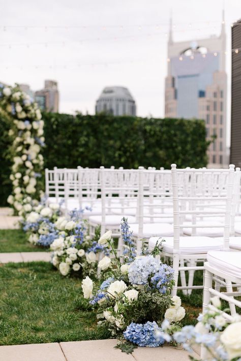 Wedding ceremony decorations for Kati & Bryant’s elegant Nashville wedding. We decorated their wedding ceremony with an elegant wedding arch, blue and white wedding flowers and hydrangeas, and white wedding chairs. Their beautiful light blue and white wedding color palette was perfect for their elegant wedding décor. We offer luxury wedding planning in Nashville and beyond. Nashville wedding venues Hydrangea Wedding Aisle, Light Blue And White Wedding, White Wedding Chairs, White Wedding Color Palette, Blue And White Hydrangea, White Hydrangea Wedding, Rooftop Wedding Ceremony, Blue Hydrangea Wedding, Baby Blue Weddings