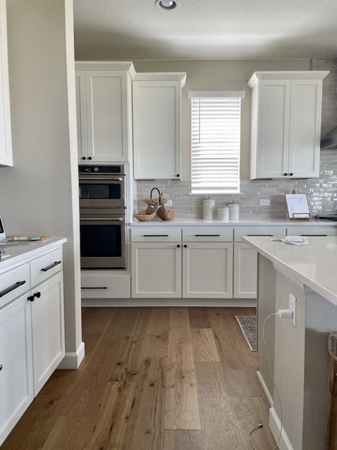 A kitchen painted with SW Accessible Beige and SW Pure White cabinets. Learn all about Accessible Beige in this paint color review. Floor Color With White Cabinets, Accessible Beige Walls With White Cabinets, Accessible Beige Sherwin Williams Color Scheme, Beige Walls In Kitchen, Accessible Beige Whole House Color Scheme, Accessible Beige Sherwin Williams Kitchen Walls, White Kitchen Cabinets Beige Walls, Accesible Beige Sherwin Williams Kitchen Cabinets, Accessible Beige With Alabaster Trim