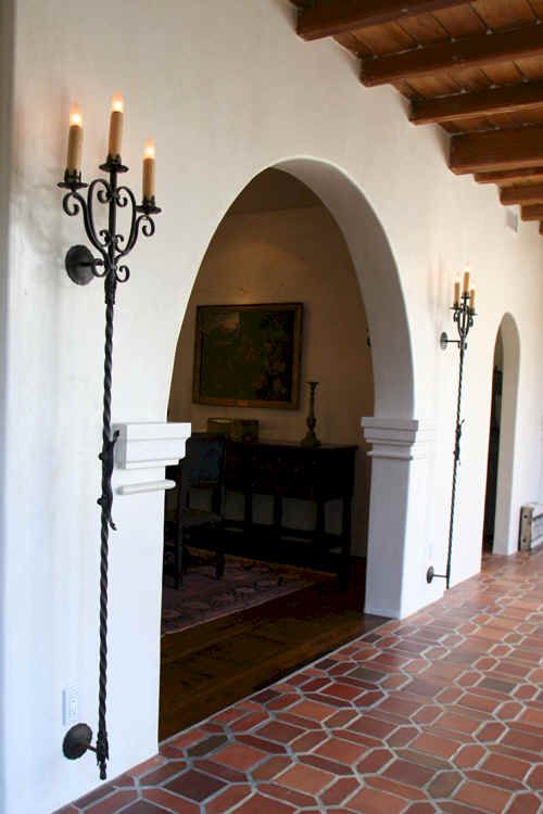 an arched doorway leading to a living room with two candles on the wall and a couch in the background