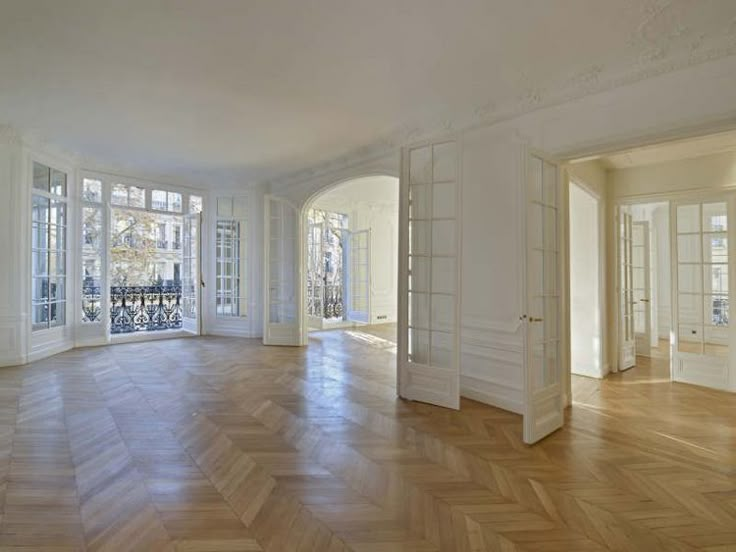 an empty room with wooden floors and large windows