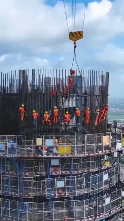 construction workers on top of a building being lifted by a crane over the cityscape