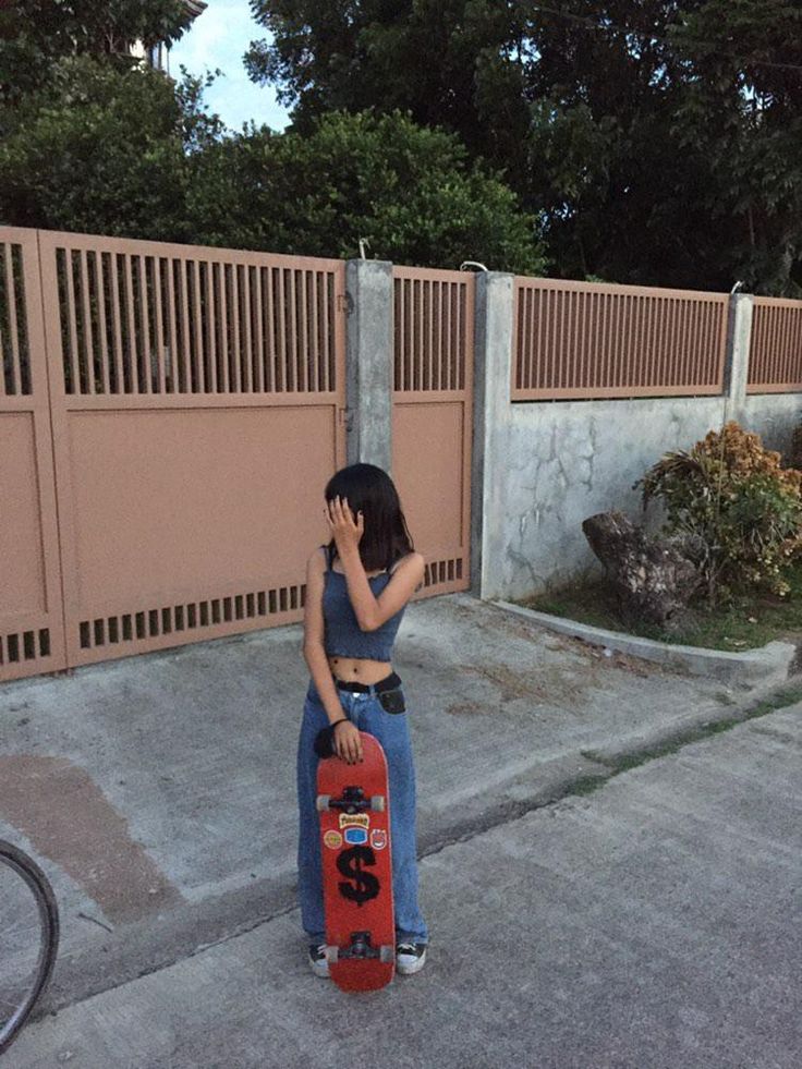 a woman is talking on her cell phone while holding a skateboard