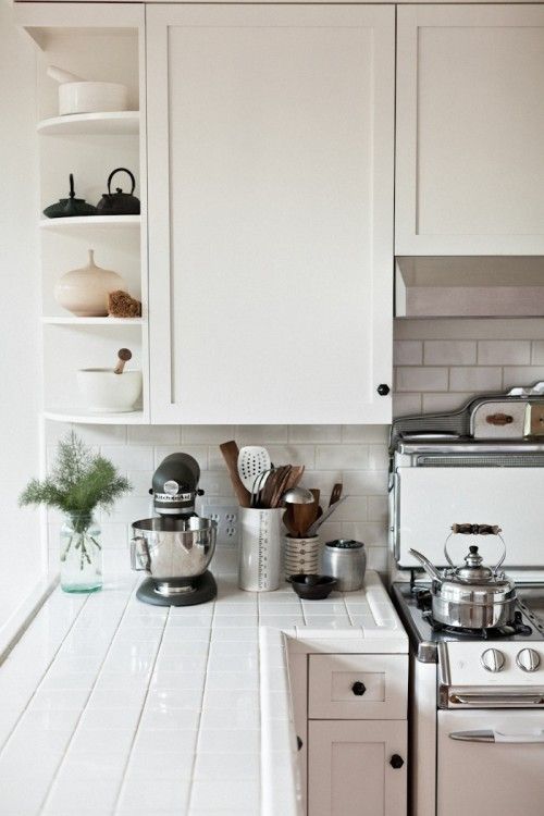 a white kitchen with pots and pans on the stove top next to an oven