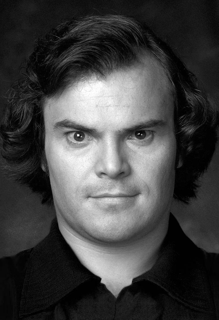 a black and white photo of a man with curly hair looking at the camera while wearing a collared shirt