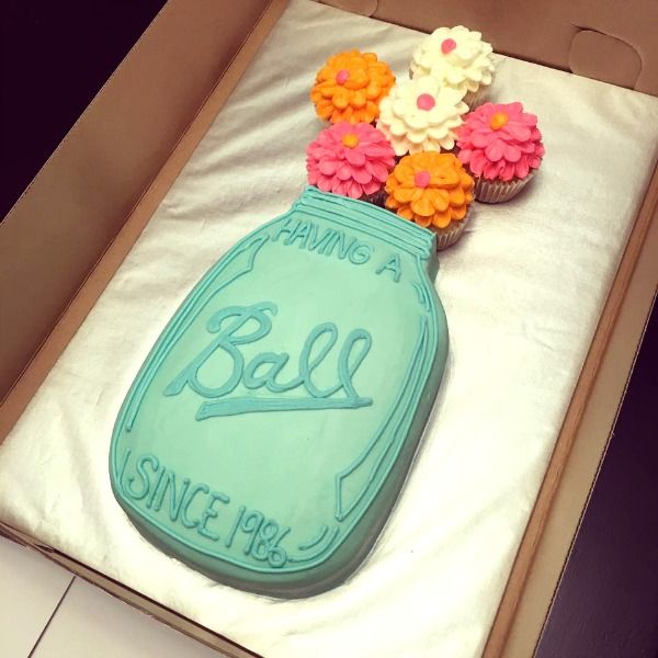 a decorated cake in the shape of a mason jar with flowers on top and saying'having a ball since july '