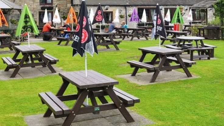 several picnic tables with flags on them in the middle of a grassy area next to a building