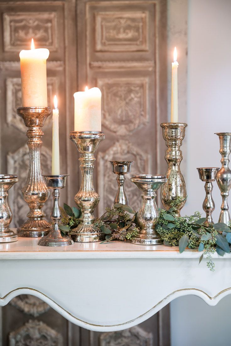 silver candles are lined up on a mantle