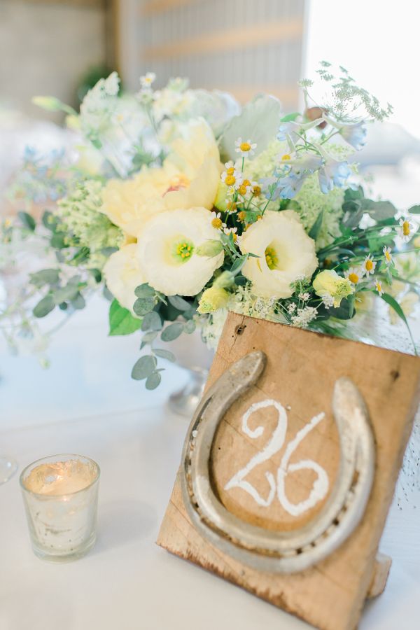 the table is set with white flowers and an old - fashioned horseshoe as centerpiece