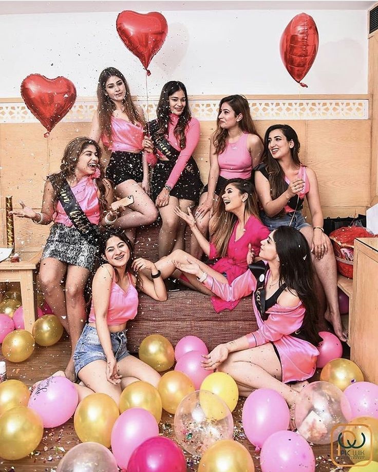 a group of women posing for a photo in front of balloons and confetti