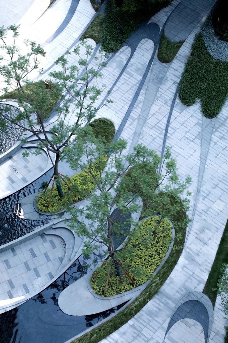 an aerial view of a park with benches and trees in the center, surrounded by water