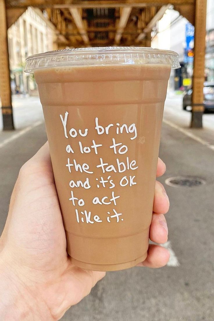 someone holding up a cup with writing on it that says you bring a lot to the table and it's ok to act like it