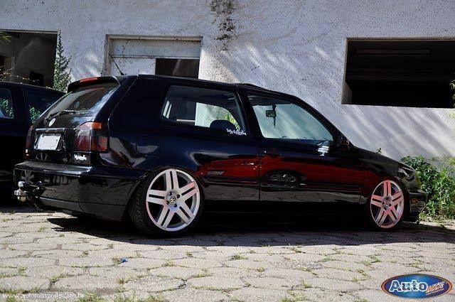 two cars parked next to each other in front of a white building with red rims