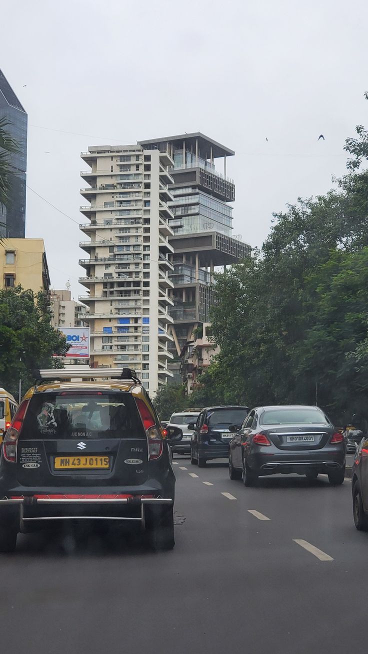 cars driving down the road in front of tall buildings