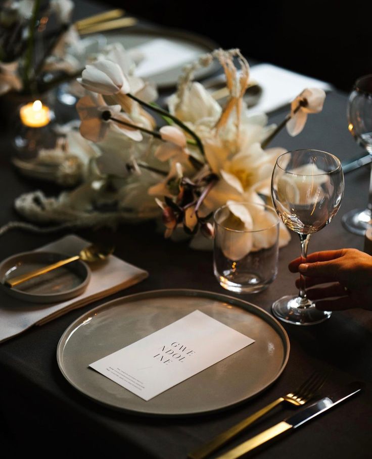 the table is set with silverware and white flowers