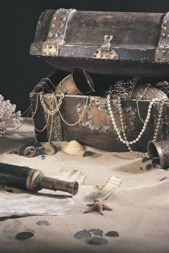 an old trunk is sitting on the sand next to shells and other items that are scattered around it