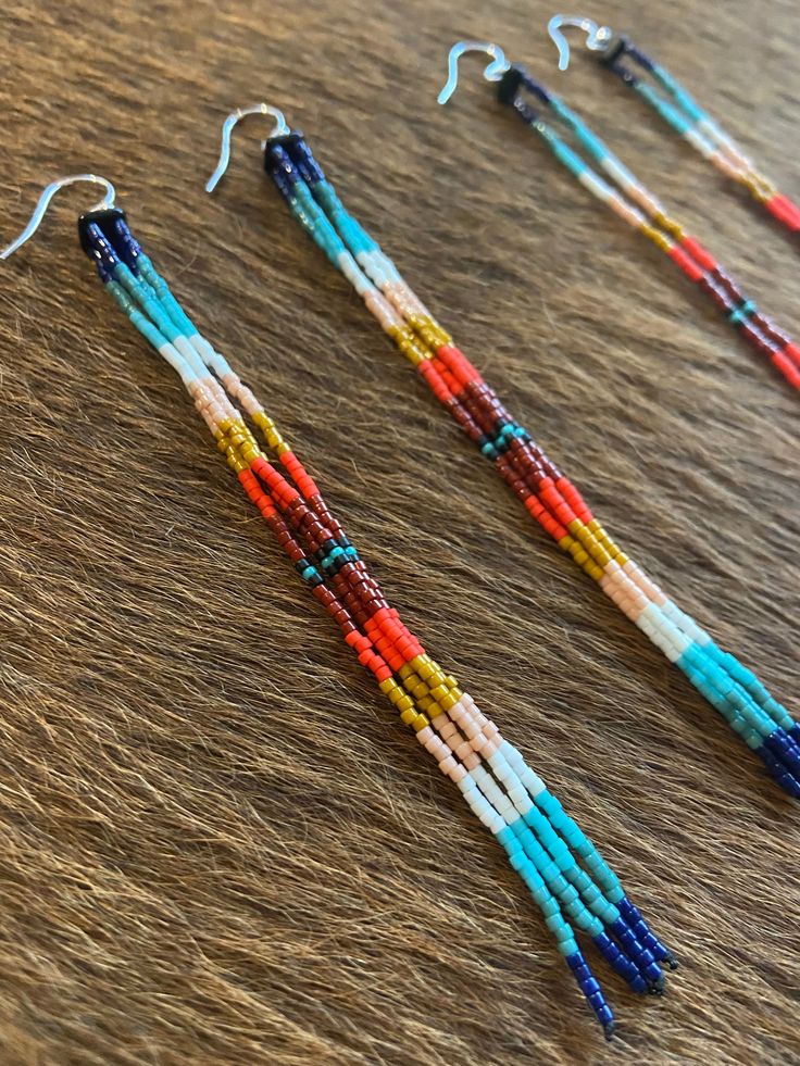 three pairs of beaded earrings sitting on top of a wooden table next to each other