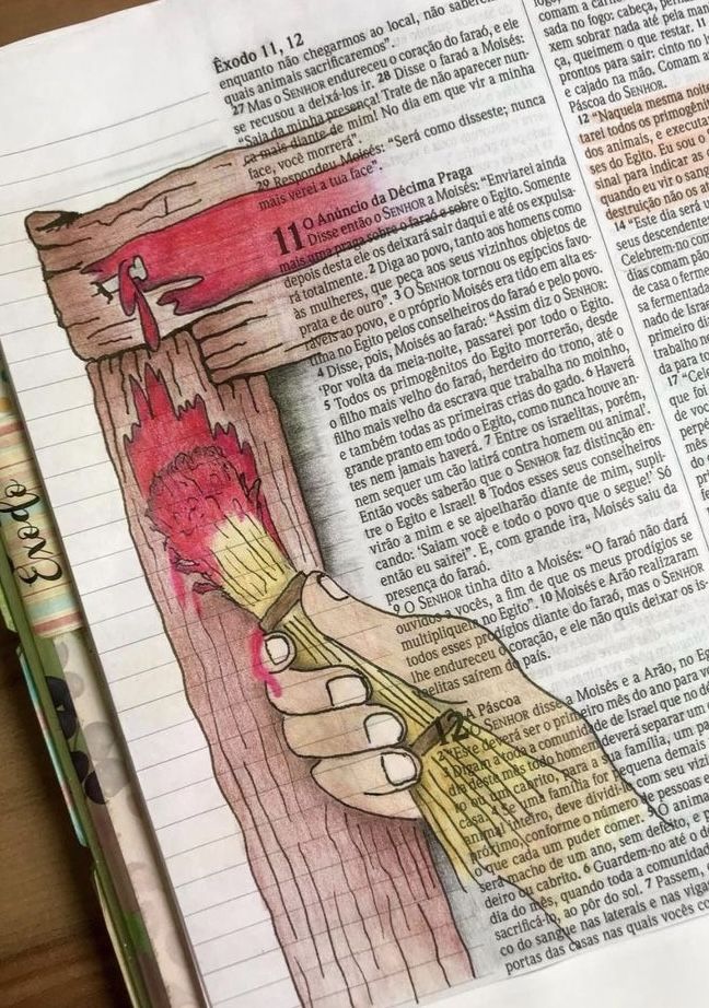 a hand holding a brush on top of an open bible