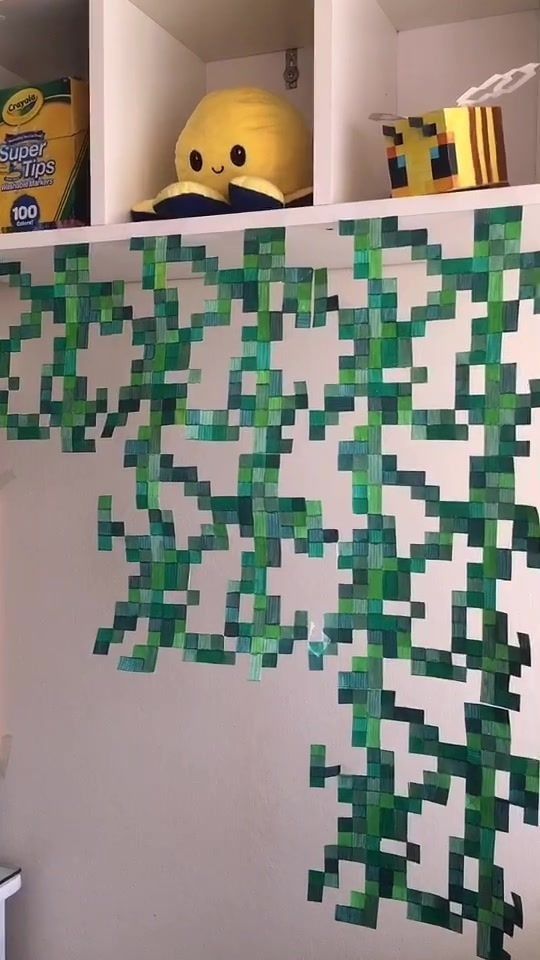 a wall with green squares on it in the shape of lego blocks and a yellow toy