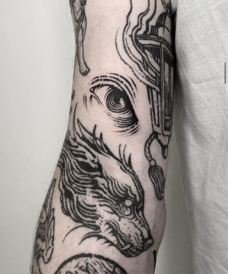 a man's arm with tattoos on it and a dragon in the middle of his arm