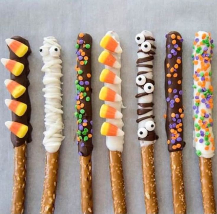 six halloween pretzels lined up in a row with candy eyes and sprinkles on them