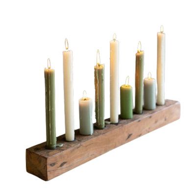 seven candles are lined up in a row on a wooden stand with one candle lit