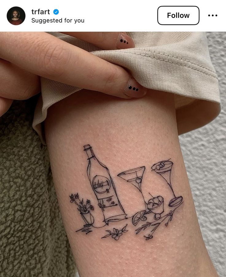 a woman with a tattoo on her arm holding a wine bottle and two martini glasses