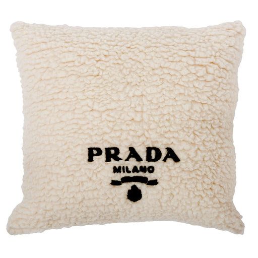 a white pillow with the word prada on it and a black outline in front