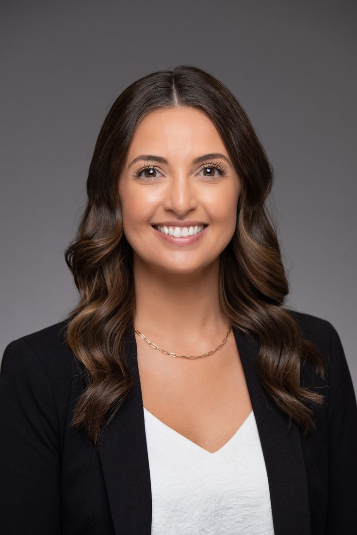 a smiling woman wearing a black blazer and white shirt