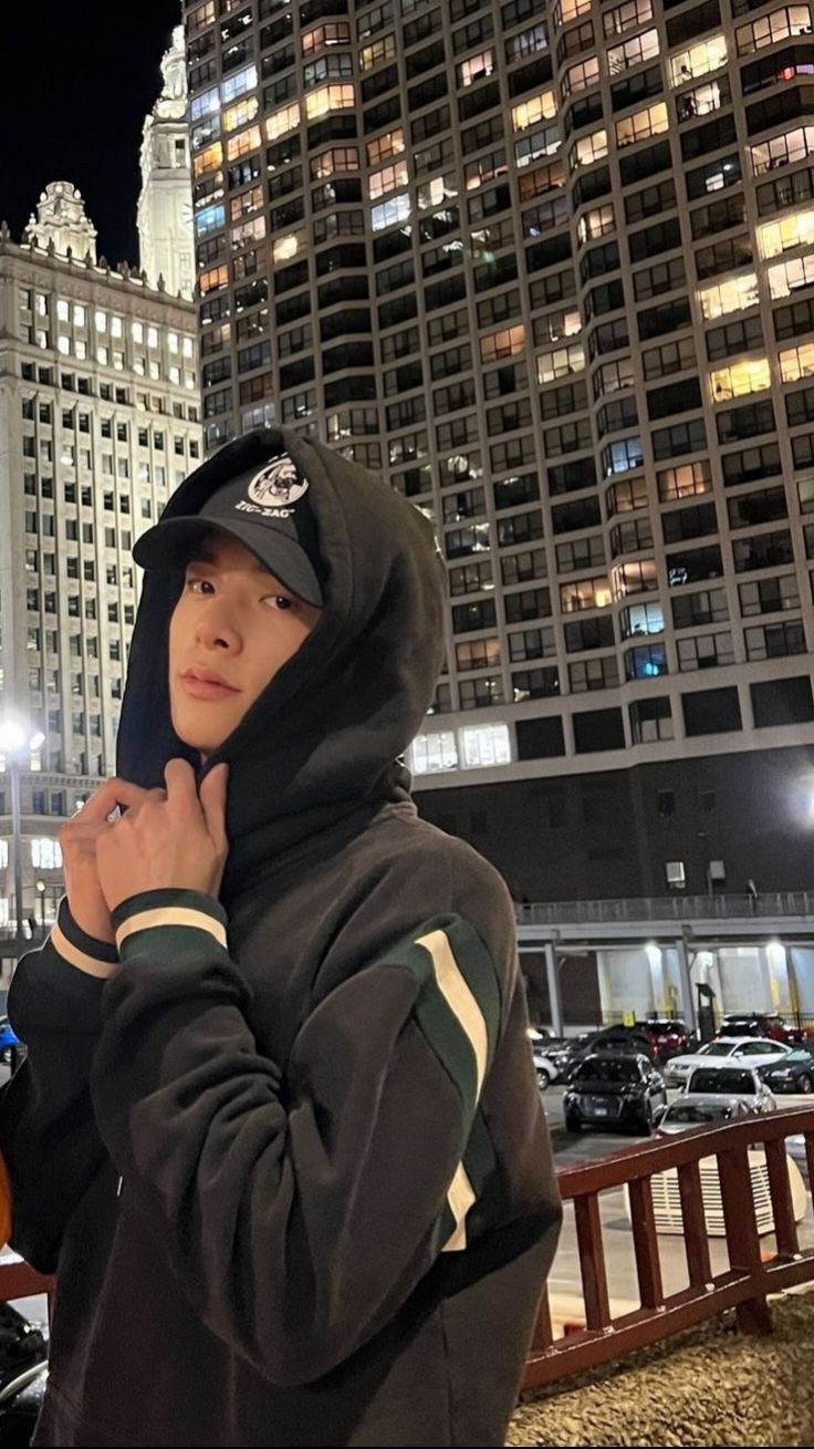 a young man standing next to a fire hydrant in front of tall buildings at night