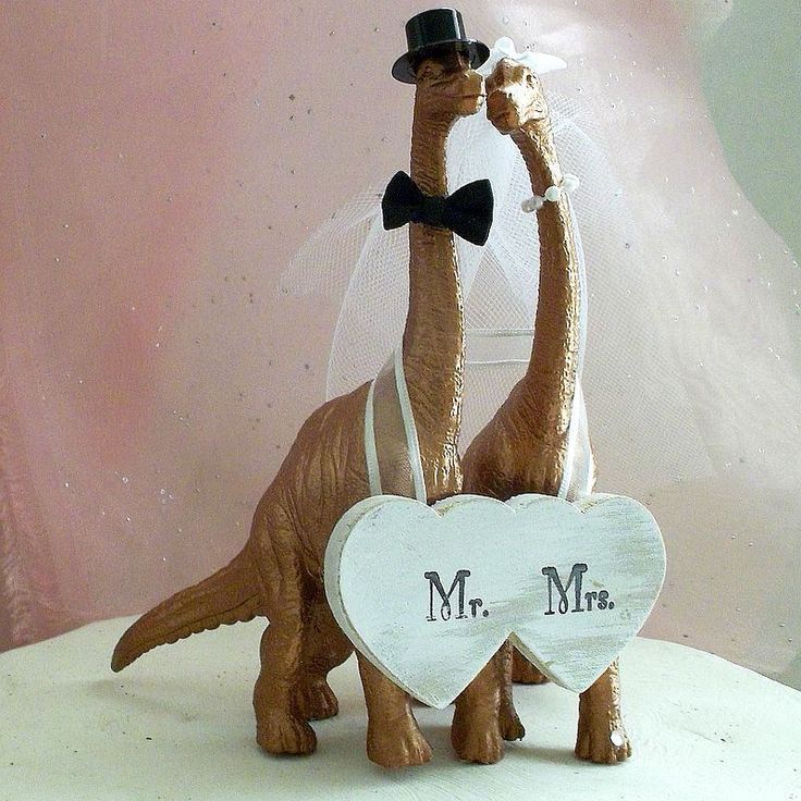 a wedding cake topper with a dinosaur holding a heart