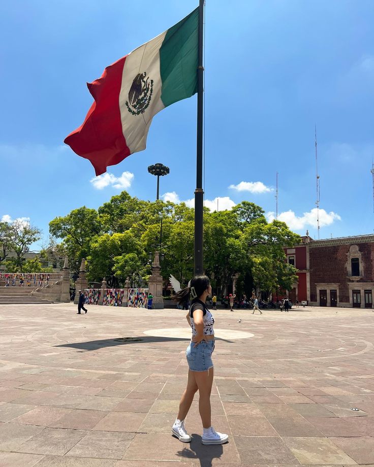 a woman standing in front of a mexican flag