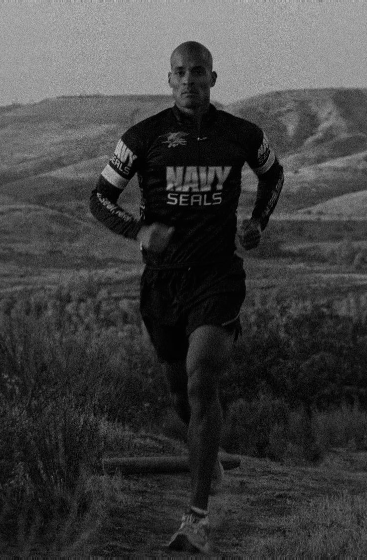 a man running down a dirt road with mountains in the background