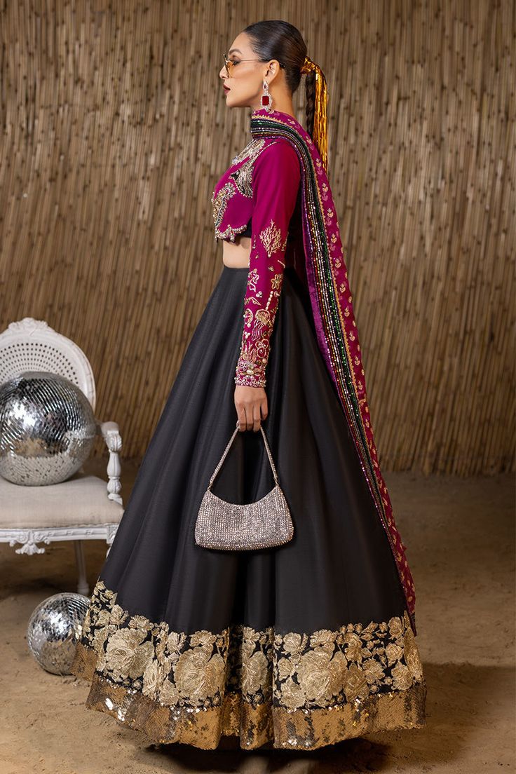 Raw Silk Black Lehenga Choli Pakistani Wedding Dresses are fully embellished with work of dabka, sequins, beads, and pearls on a long frock lehenga. It is worn over a beautiful plain silk lehenga and is paired with a Bright Pink Maisuri dupatta Purple Choli Lehenga: A black raw silk lehenga choli comes in a purple short choli with sequins, an embroidered border, and edging with a plum raw silk embellished choli and plum embellished and embroidered raw silk dupatta. Black Lehenga: Pakistani weddi Indian Wedding Outfits Black, Black Lehanga Ideas, Black Anarkali For Wedding, Traditional Embroidered Lehenga, Lehnga Dress Indian Weddings, Black And Pink Lehenga, Black Lehenga Outfit, Black Lehenga Party Wear, Purple Choli