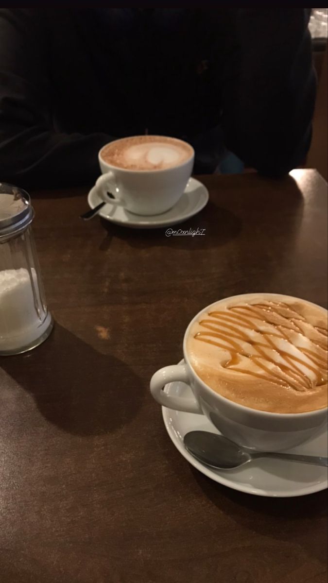 two cups of coffee sitting on top of a table