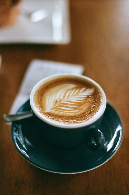 a cappuccino on a saucer with a leaf pattern in the foam