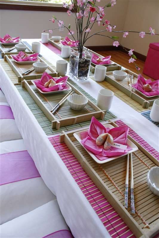 the table is set with pink napkins and place settings for two people to eat