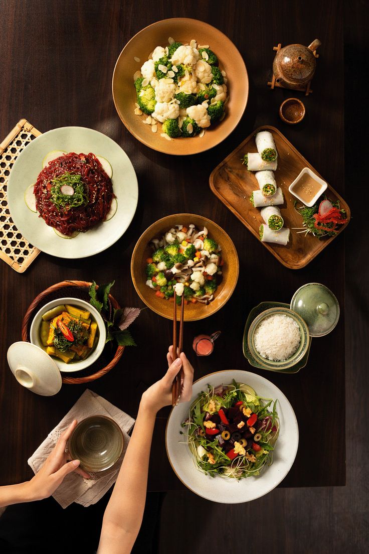 a table topped with plates and bowls filled with different types of food next to utensils