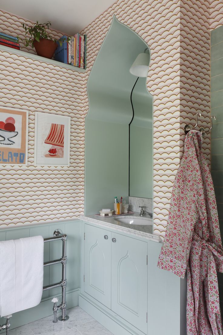 the bathroom is decorated in pastel colors and features an arch - shaped mirror over the sink