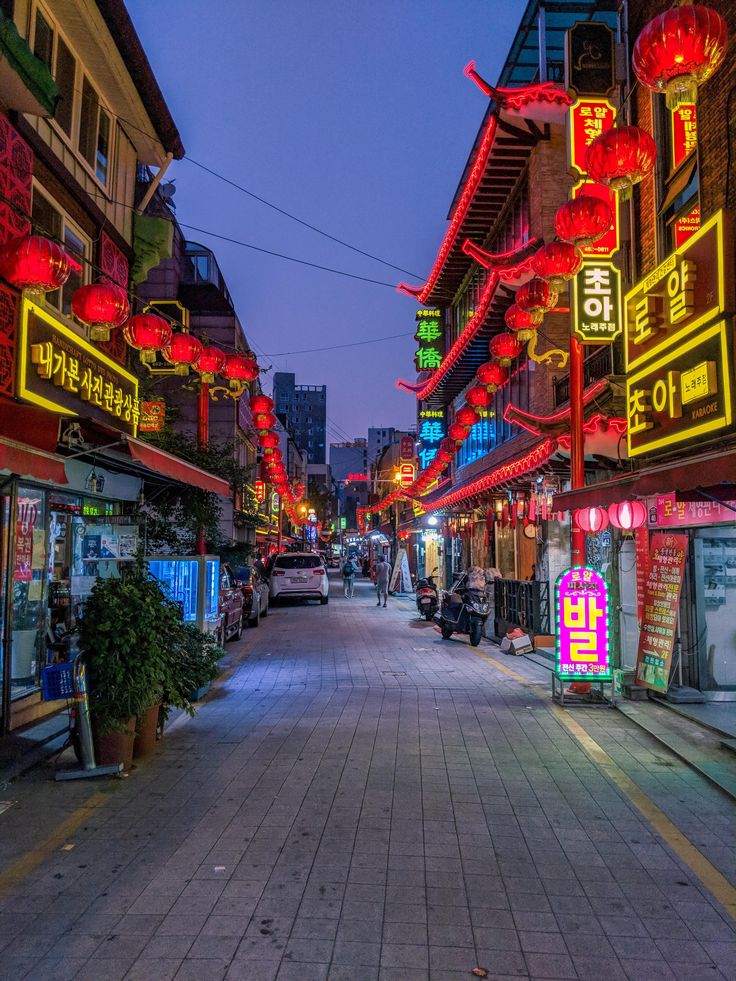 an empty street is lit up with red and yellow lanterns in the city at night