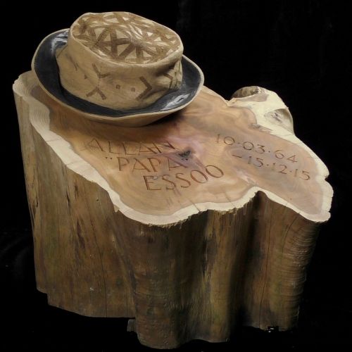 a hat is sitting on top of a piece of wood that has writing on it